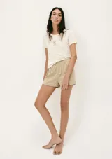 Pijama compuesto por una remera de algodón color crema con estampa pequeña en el pecho y un short de tela liviana color beige con estampado de cuadrícula fina.