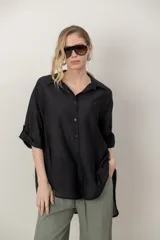 Camisa oversize de seda negra, con cuello camisero, cierre frontal con botones y mangas cortas con vuelta.