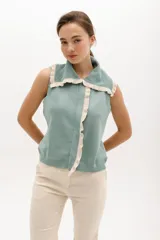 Chaleco de punto color verde menta, sin mangas, con cuello solapa y ribetes de volados en contraste color beige.