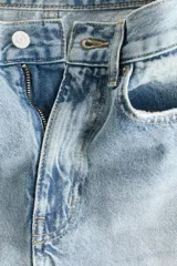 Jean de cinco bolsillos en denim de algodón rígido, con diseño de piernas curvas y volumen, de corte holgado desde la cadera hasta los muslos y ligeramente más ceñido en el bajo. Cintura clásica con cierre de botón y cremallera.
