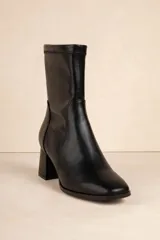 Botas negras de caña media en símil cuero, con cierre lateral y punta redondeada. Taco cuadrado de 6,5cm de alto.