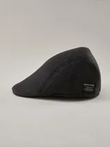 Boina estilo flat cap de Benson & Thomas, color gris con patrón de cuadros escoceses, con etiqueta de marca en el lateral.