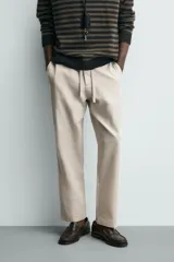 Pantalón de corte relajado confeccionado en una mezcla de algodón y lino. Presenta cintura elástica con cordón ajustable, bolsillos laterales y bolsillos traseros de vivo.
