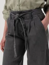 Pantalón de jean color gris con efecto lavado, de corte recto y tiro alto. Cuenta con cintura elástica en la parte posterior, cierre frontal con lazo ajustable y bolsillos laterales.