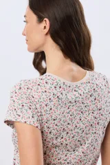 Remera blanca de manga corta con estampado floreado, cuello redondo y detalle de botones frontales.