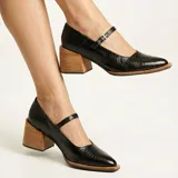 Zapato tipo Mary Jane de cuero vacuno con textura grabada, color marrón oscuro. Presenta una puntera cuadrada, taco bloque de madera y una tira con hebilla metálica sobre el empeine.