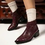 Bota corta de cuero vacuno con acabado metalizado y textura de reptil. Presenta punta fina, cierre lateral interno y taco cuadrado de madera.