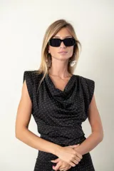 Blusa negra con lunares blancos, cuello drapeado y corte ajustado.