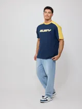 Remera negra de algodón con corte en hombros y mangas, cuello redondo gris oscuro y ribete blanco en los hombros. Estampado frontal con el texto "RUSTY" en tipografía futurista blanca con borde gris.