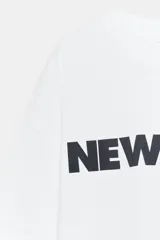 Remera oversize blanca de algodón con cuello redondo, manga corta y estampa con la inscripción 'NEW YORK' en color negro en el frente.