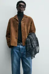 Sobrecamisa de corte relajado confeccionada en piel con acabado de ante. Presenta cuello tipo bowling, cierre frontal con botones, manga larga con puños abotonados y bolsillos de vivo en la parte frontal.