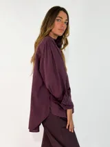 Camisa de algodón color blanco, con cuello redondo y detalle de volados en el cuello y puños. Presenta mangas largas con puños elásticos y un diseño de corte holgado con ruedo asimétrico, más largo en la parte trasera.