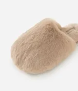 Pantufla cerrada de peluche color beige, con suela plana y diseño cómodo para el hogar.