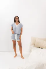 Pijama de algodón color gris, compuesto por una remera de manga corta con escote en V y puntilla blanca, y un short con elástico en la cintura, lazo blanco y terminación con puntilla blanca.