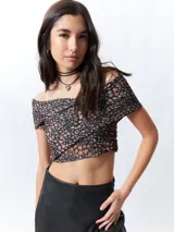 Top negro con estampado floral, escote off-shoulder, corte cruzado y mangas cortas.