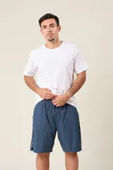 Bermuda deportiva de nylon color gris, de corte suelto, con cintura elástica y cordón de ajuste. Cuenta con detalles de líneas negras en los costados y bolsillos laterales con cierre.