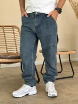 Pantalón tipo carpenter de denim azul con corte holgado, bolsillos laterales utilitarios y cierre frontal con botón.