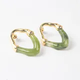 Caravanas de diseño geométrico con estructura metálica dorada y pieza de resina en color verde con destellos brillantes.