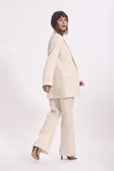 Blazer color crema con textura de lurex, solapas clásicas, corte recto y bolsillos delanteros.
