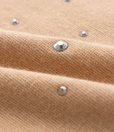 Remera de malla color tostado con cuello redondo, mangas cortas y aplicación de strass salpicado en toda la prenda.