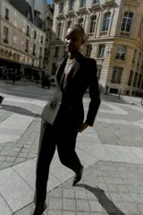 Blazer entallada de color negro con cuello solapa, manga larga y hombreras marcadas. Presenta cierre frontal con dos botones dorados y bolsillos delanteros con solapa.