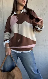 Sweater de punto con diseño de bloques de color en tonos chocolate, rosa y beige, de corte oversize y cuello redondo.
