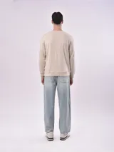 Buzo color beige claro con cuello redondo y puños y cintura acanalados. Estampado frontal con texto en color gris.