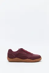 Zapatilla de estilo barefoot color bordó, con diseño de paneles combinados en diferentes texturas y suela de goma flexible en tono caramelo con relieve.