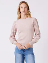 Buzo de tejido lurex marca Nanette, con cuello redondo y mangas largas con diseño plisado. Presenta puños ajustados con aplique de botones decorativos.