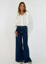 Pantalon de jean azul oscuro, de corte wide leg con botamanga deshilachada y tiro medio.