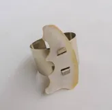 Brazalete rígido plateado con pieza irregular de nácar incrustada.