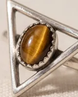 Anillo de plata con diseño triangular y piedra central de ojo de tigre ovalada.