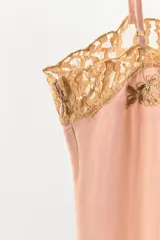 Body de satén color rosado con escote recto, tirantes finos ajustables y detalles de encaje en contraste. Presenta bordados florales con abalorios en el frente y cierre inferior con botones a presión.