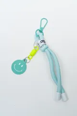 Llavero de cordón celeste con mosquetón metálico, etiqueta con logo, resorte amarillo y dije circular con carita feliz.
