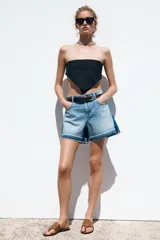 Shorts de jean de tiro medio, corte mom fit, con efecto lavado y terminación desflecada. Presenta cinco bolsillos y cierre frontal con cremallera y botón.