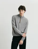 Sweater de punto azul con medio cierre frontal, cuello alto y detalles en símil nappa en la cartera del cierre y coderas.