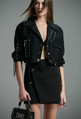 Minifalda negra de corte envolvente con detalle de botones metálicos y bolsillo de parche.