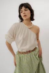 Blusa de un solo hombro color crudo con diseño asimétrico y manga larga abullonada.