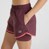 Short deportivo New Balance 2-in-1 para mujer, color borgoña con detalles en rosa. Cuenta con short interior de 4.5" y exterior de 3", tecnología NB DRY de secado rápido, bolsillos laterales y logo reflectivo.