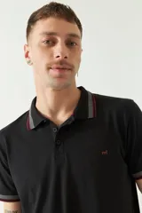 Remera polo negra de manga corta con ajuste regular. Presenta cuello y puños con ribete a rayas en gris y bordó. El logo de la marca está estampado en el pecho.