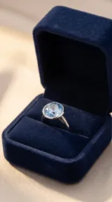 Anillo de plata con engaste circular y cristal facetado de color celeste.