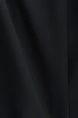 Vestido corto negro sin mangas, con escote redondo, cuerpo entallado y falda acampanada con frunces caídos en la cadera.