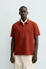 Polo de hombre color terracota con cuello solapa y cierre frontal de botonadura. Presenta un tejido texturizado tipo seersucker y un calce relajado.