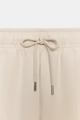 Pantalón de tiro medio confeccionado en tejido de punto elástico con pierna recta. Cuenta con cintura elástica ajustable mediante cordones y bolsillos laterales.