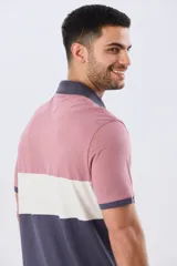 Remera polo de manga corta con diseño en bloques de color en tonos azul marino, blanco y verde militar, con bordado frontal y cierre de botones.
