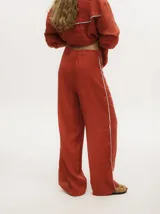 Pantalón de lino color marrón claro, de pierna ancha y tiro alto. Presenta un pequeño elástico en la parte trasera de la pretina y detalle al costado tipo naval.