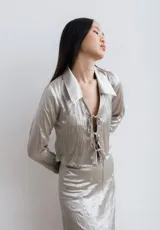 Camisa corta de seda negra con cuello clásico y lazos para anudar en el frente.