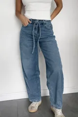 Pantalón de jean estilo mom fit en tono azul clásico, con diseño de tiro alto y lazo ajustable en la cintura. Presenta un corte relajado y holgado en las piernas, confeccionado en denim rígido con estructura.