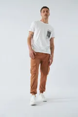 Pantalón cargo color marrón con corte slim, elástico en cintura y cordón ajustable, bolsillos cargo con botones y puños elásticos. Confeccionado en algodón y spandex.