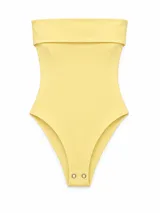 Body color amarillo pastel, sin mangas, con escote tipo palabra de honor (strapless) y solapa superior. Cuenta con cierre de broches a presión en la parte inferior.